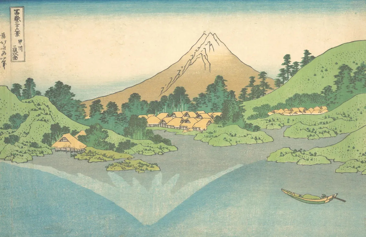 Fuji Dağı'nın durgun gölde baş aşağı yansıması; kıyıda yeşil tepeler ve küçük bir köy. Japon ahşap baskısı.