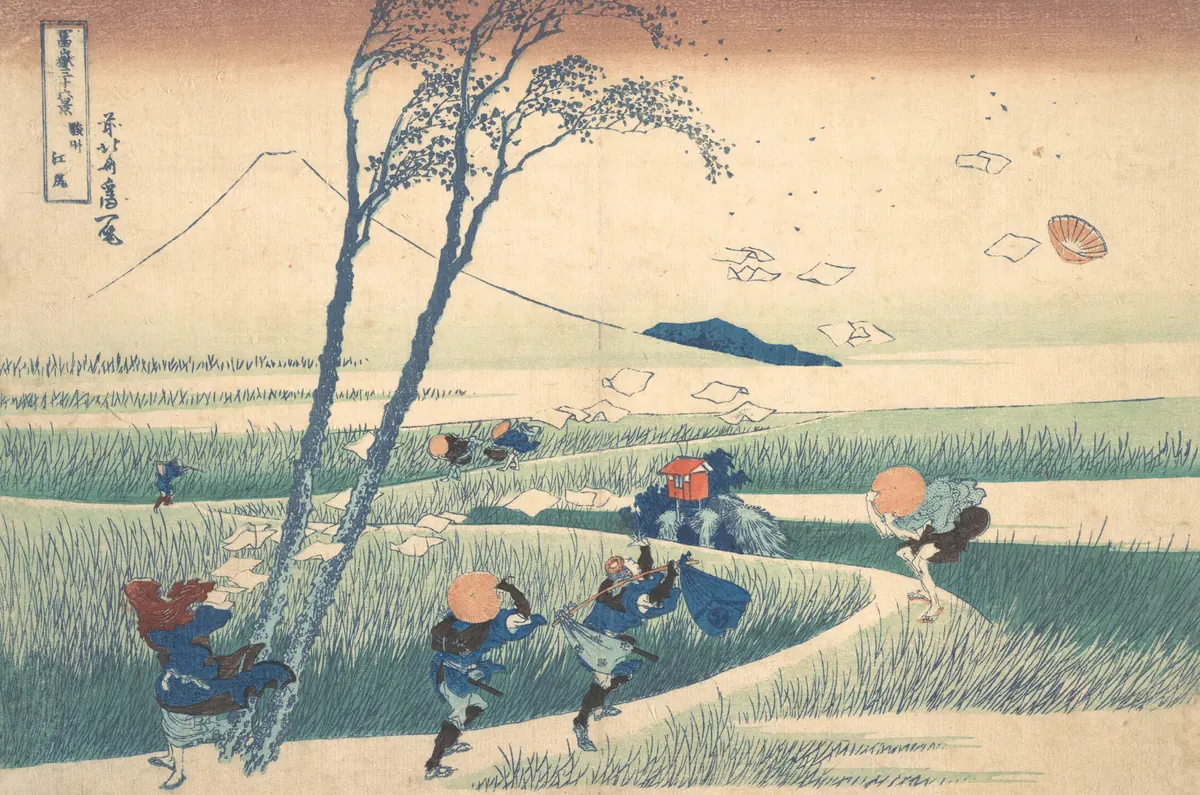 Sert rüzgârın savurduğu yolcular, eğilen ağaçlar ve havada uçuşan kâğıtlar; uzakta Fuji Dağı. Japon ahşap baskısı.